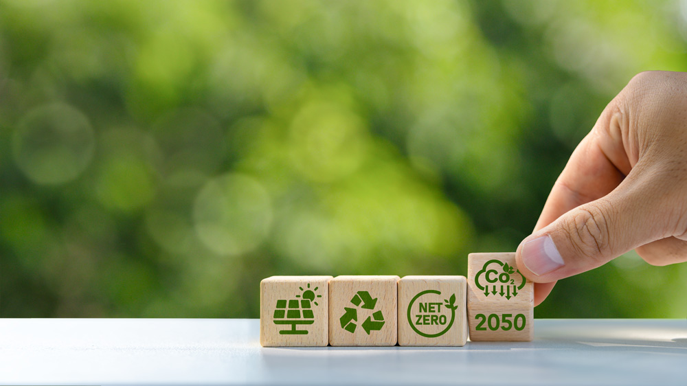 Hand placing sustainability blocks representing net zero and carbon reduction goals